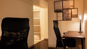 Une chambre d’hôtel dotée d’un coin repas comprenant une table et des chaises, une bibliothèque et des œuvres d’art encadrées accrochées au mur.