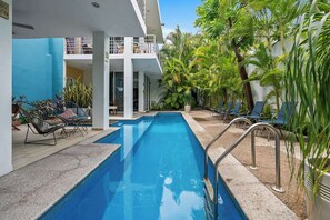 Uma piscina com espreguiçadeiras e plantas em vasos.