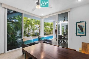A modern room with a pool, large windows, and a ceiling fan.