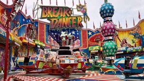 Een vrolijk themapark met diverse attracties en achtbanen, waaronder een opvallend 'Break Dancer' bord.