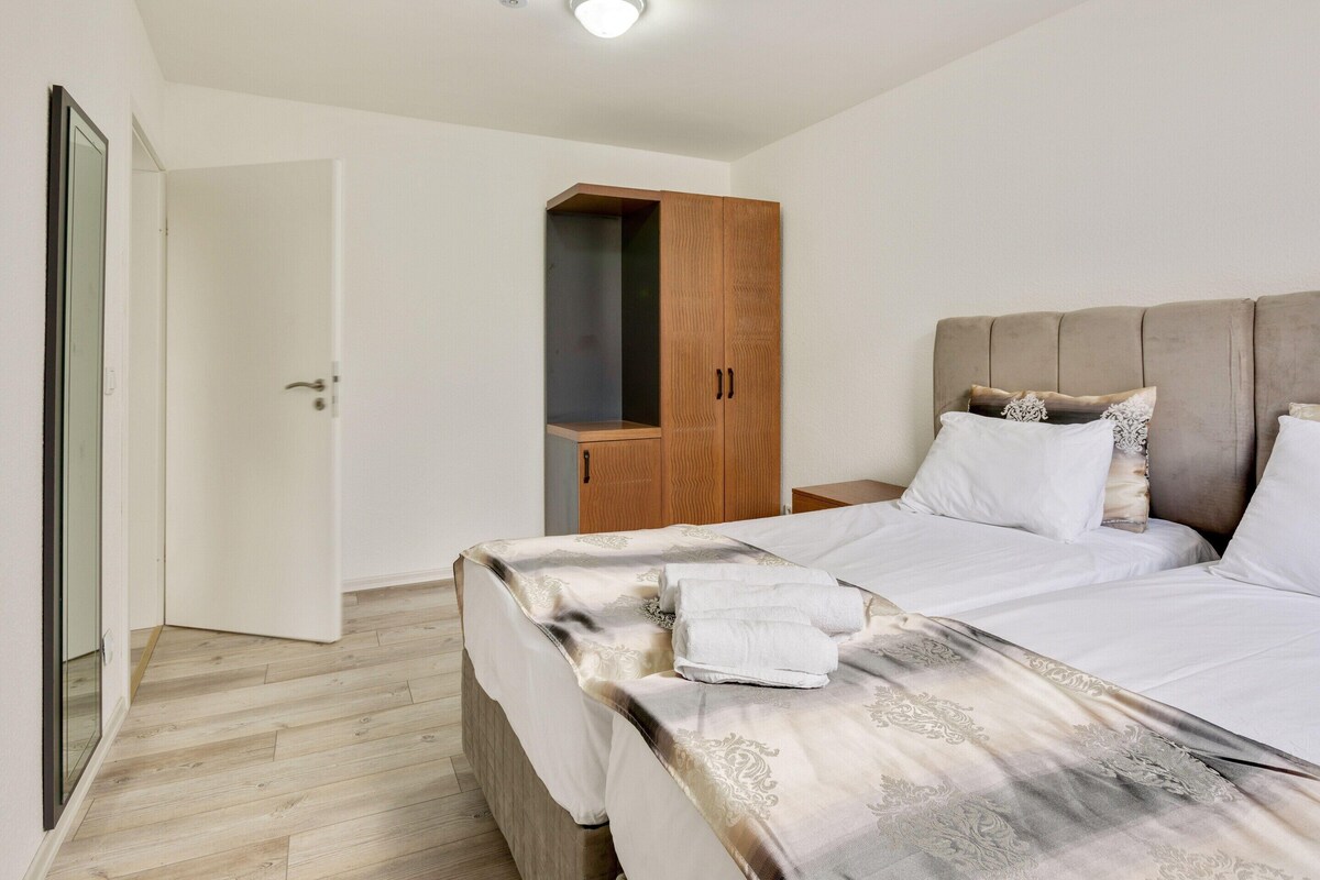 A bedroom with a bed, bedside tables, a wardrobe, and a door.