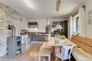 Una cocina moderna con una isla central, electrodomésticos de acero inoxidable y una pared de piedra rústica.