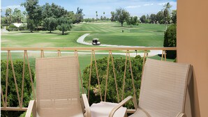Un balcón con dos sillones de mimbre que da a un campo de golf.