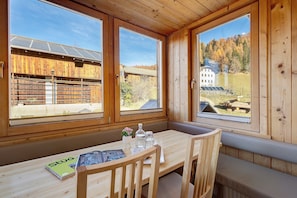 Une cabane en bois avec de grandes fenêtres, une table en bois et un banc.