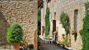 A narrow alleyway with stone buildings, a small table with chairs, and potted plants. - Charming House in Tuscany With Pool & Views (Sovicille)
