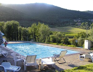 Ein Pool mit Liegestühlen und Blick auf eine hügelige Landschaft.