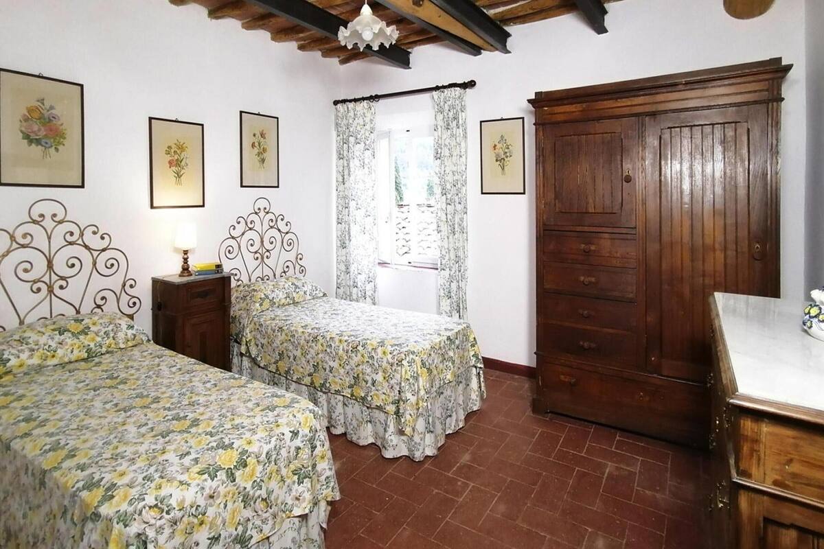 A bedroom with two beds, a wooden wardrobe, and a small bedside table with a lamp.