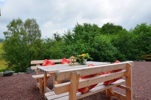 A wooden picnic table with benches, a lantern, and a potted plant. - Ferienwohnung im Sauerland (Olsberg)
