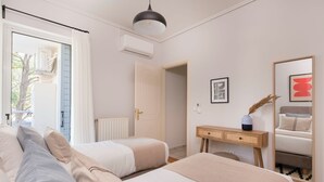 A bedroom with two beds, a dresser, a mirror, and an air conditioning unit. - Family Escape in Chalandri -Parnassidos 10 (Chalandri)