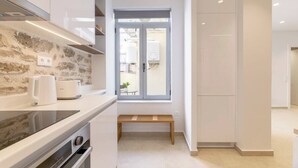 A modern kitchen with a stone backsplash, built-in appliances, and a window with a view. - Psyrri Hideout · Chic 2BR Apartment (Athina)