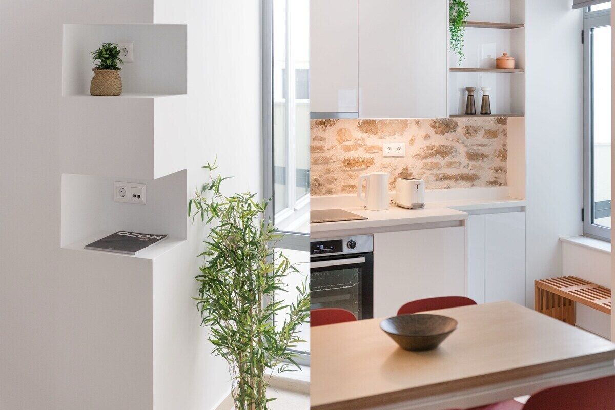 A modern kitchen with white cabinetry, a stone backsplash, and a dining area with a wooden table and red chairs.