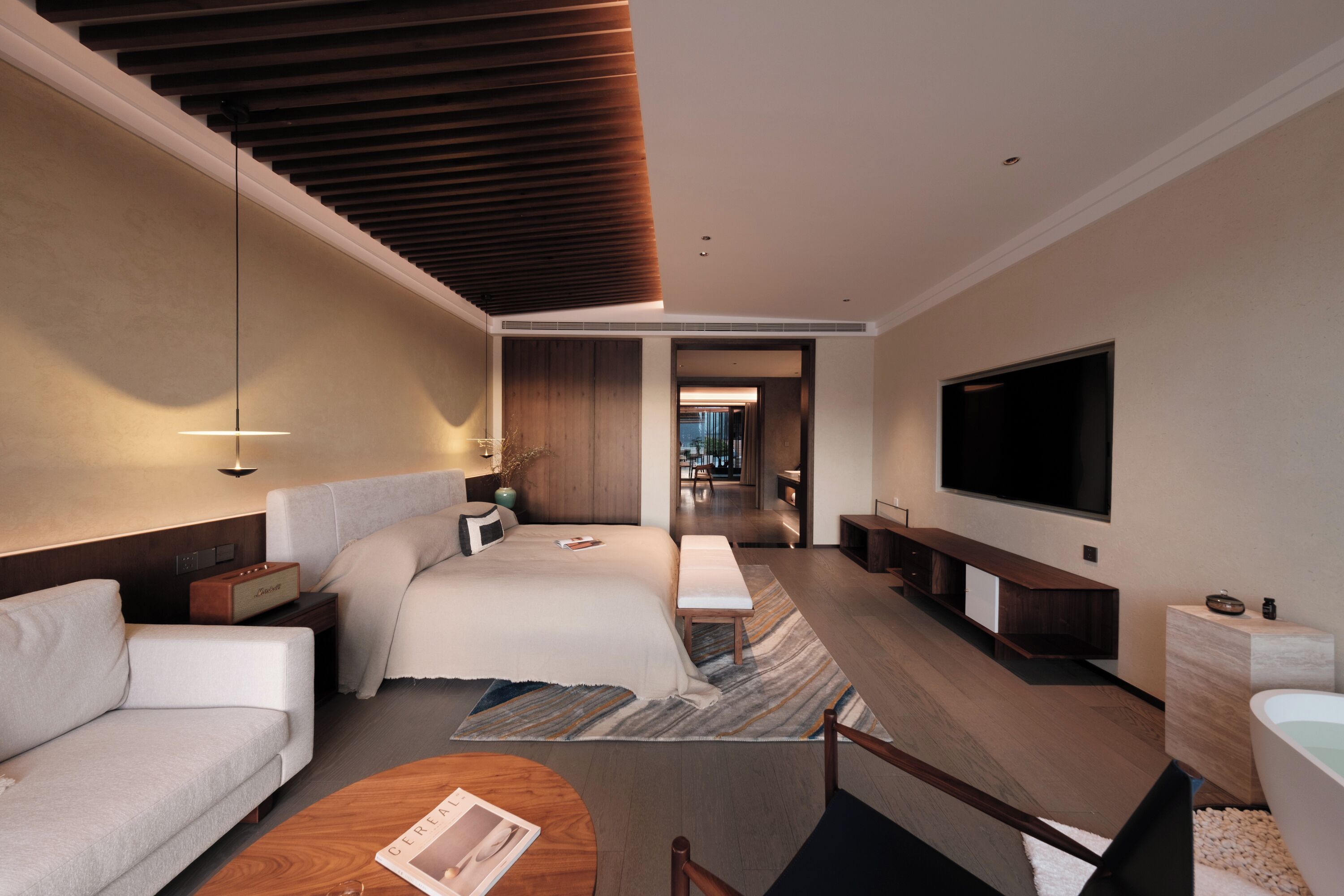 Ein modernes Hotelzimmer mit einem großen Bett, einer Couch, einem Fernseher und einem Couchtisch.