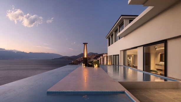 A modern building with a pool extending to the water's edge, overlooking a mountainous landscape. - Dali Puyu VILLA Cliff Seaview Hotel (Dali)