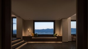 A modern interior with a large window, a built-in bench, and a staircase leading to an upper level. - Dali Puyu VILLA Cliff Seaview Hotel (Dali)