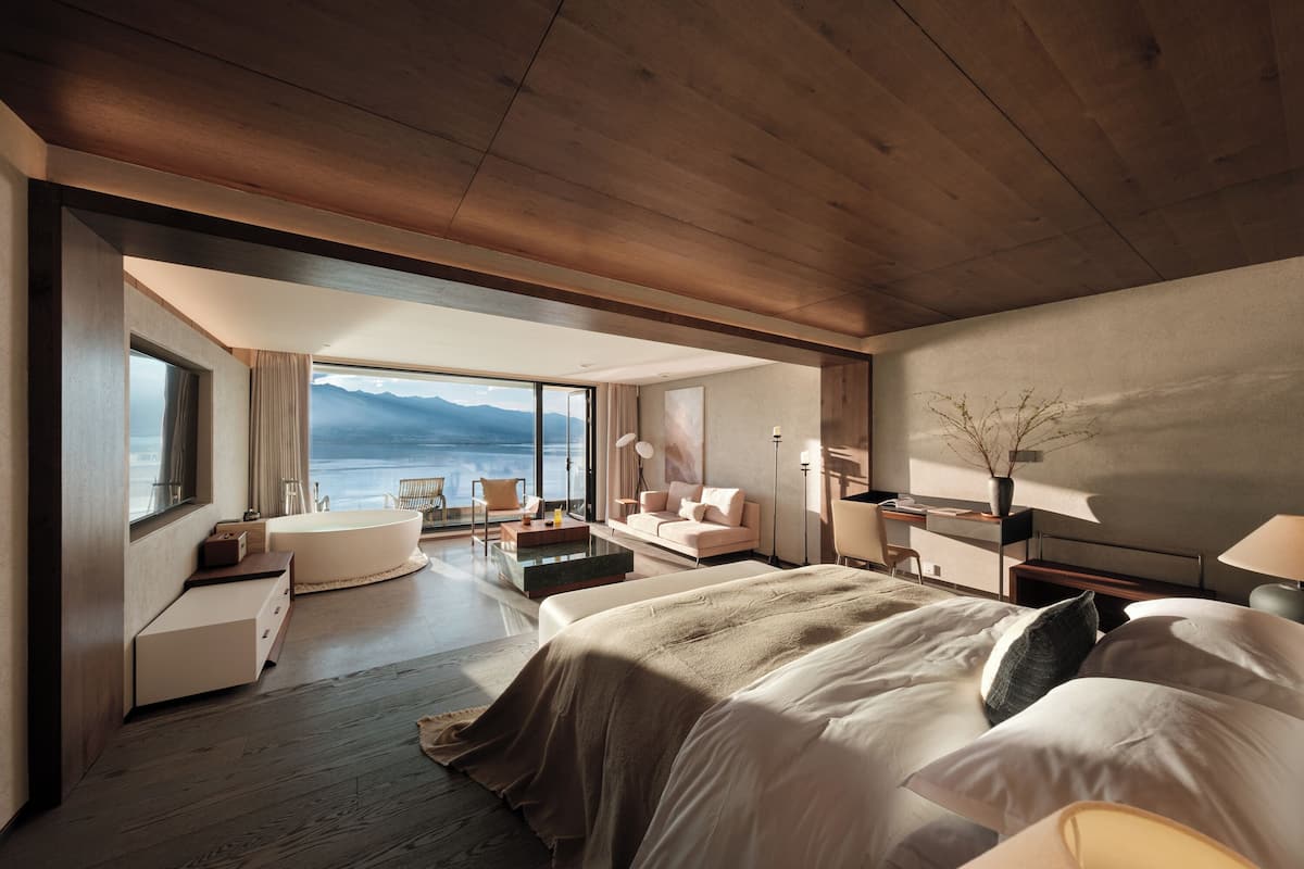 Une chambre d’hôtel moderne dotée d’un grand lit, d’un coin salon avec vue sur la mer et d’un balcon.