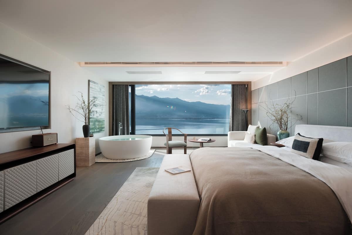 Une chambre d’hôtel moderne avec un grand lit, une baignoire, une télévision et une vue sur les montagnes.
