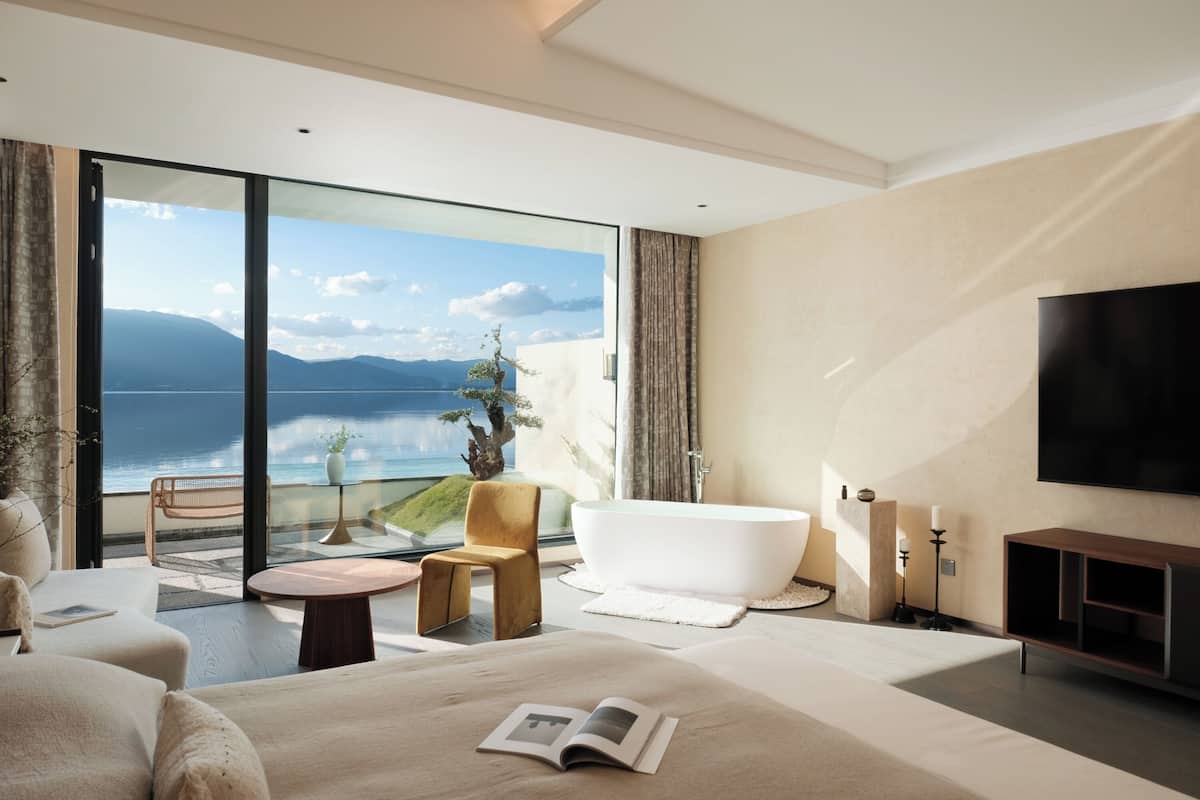 Une chambre moderne avec un grand lit, une baignoire et une vue sur la mer.