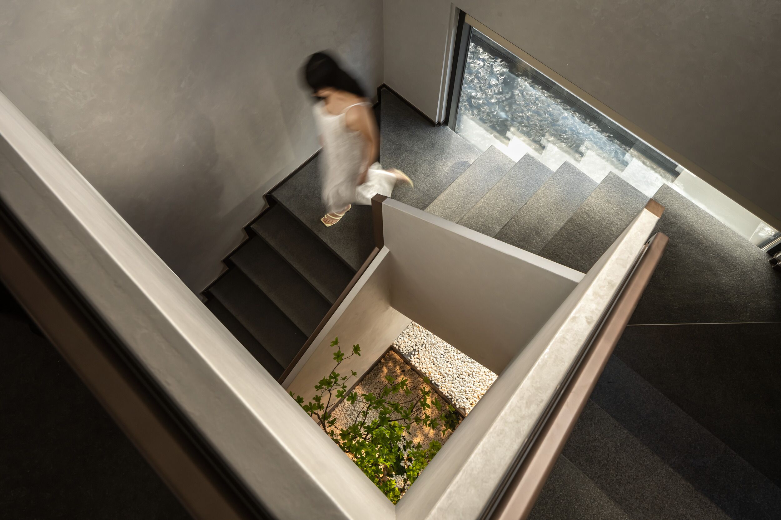 A modern staircase with a small garden area at the bottom.