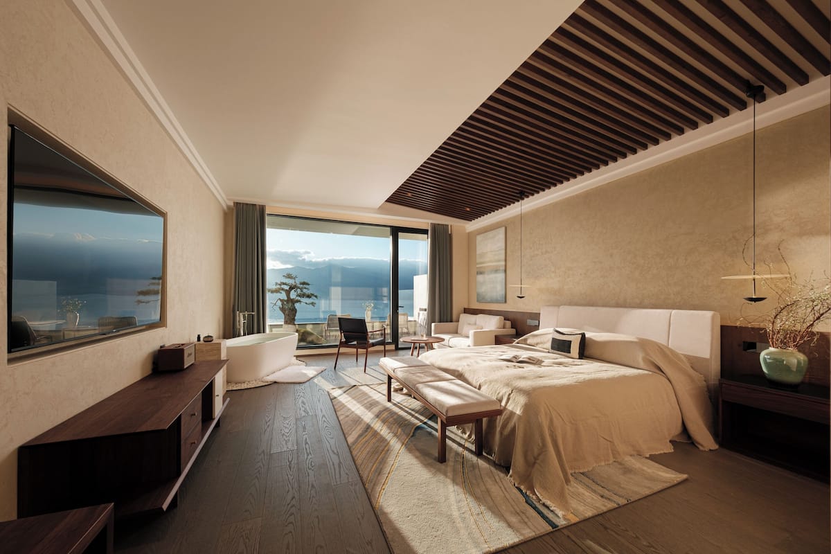 Une chambre d’hôtel moderne dotée d’un grand lit, d’un coin salon avec vue sur la mer et d’une grande fenêtre.