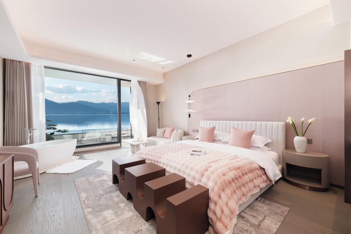 Une chambre moderne avec un grand lit, des tables de chevet, une coiffeuse et une vue sur la mer.