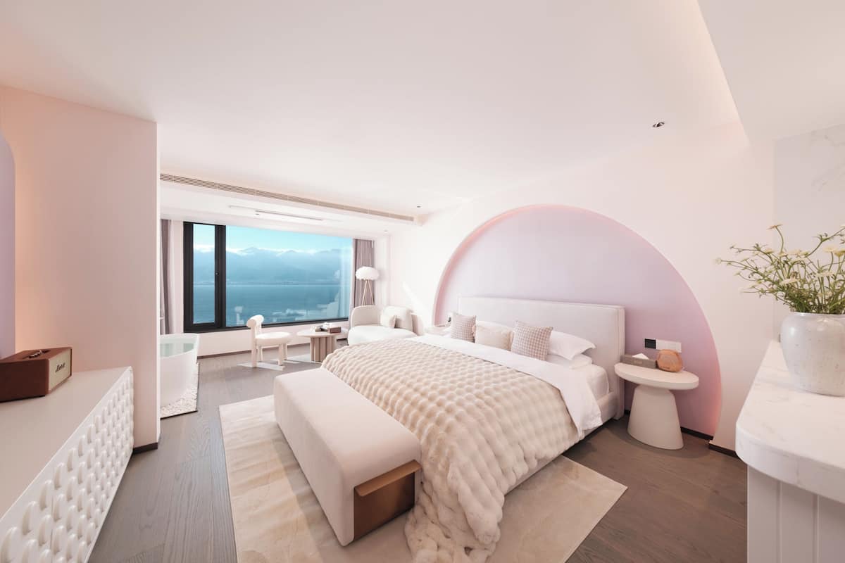 Une chambre moderne dotée d’un grand lit, offrant une vue sur les montagnes et comprenant un coin salon confortable.