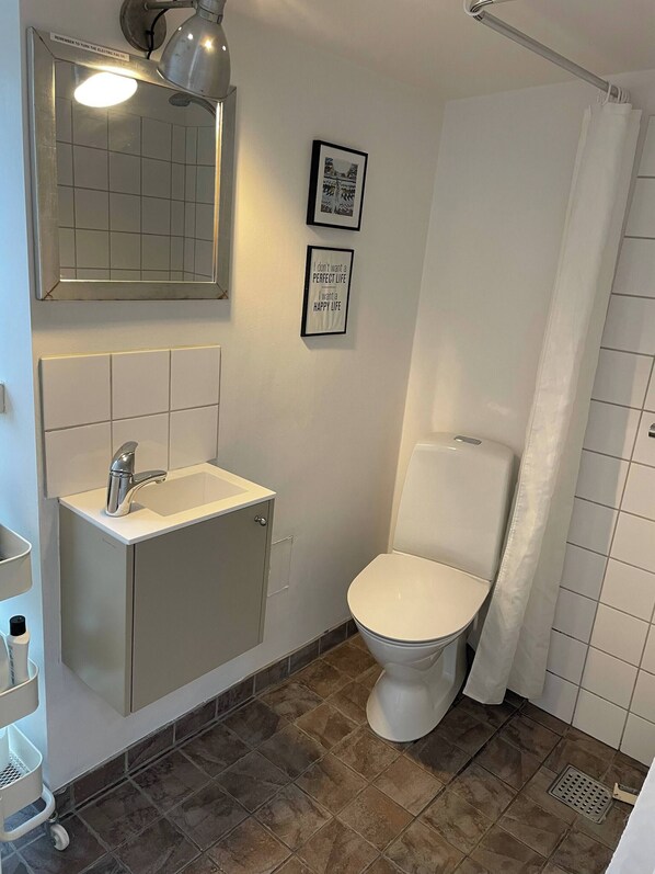 A bathroom with a white sink, mirror, and toilet. There are two framed quotes on the wall. - Charming Townhouse in Præstø Center 50 m2 (Praesto)