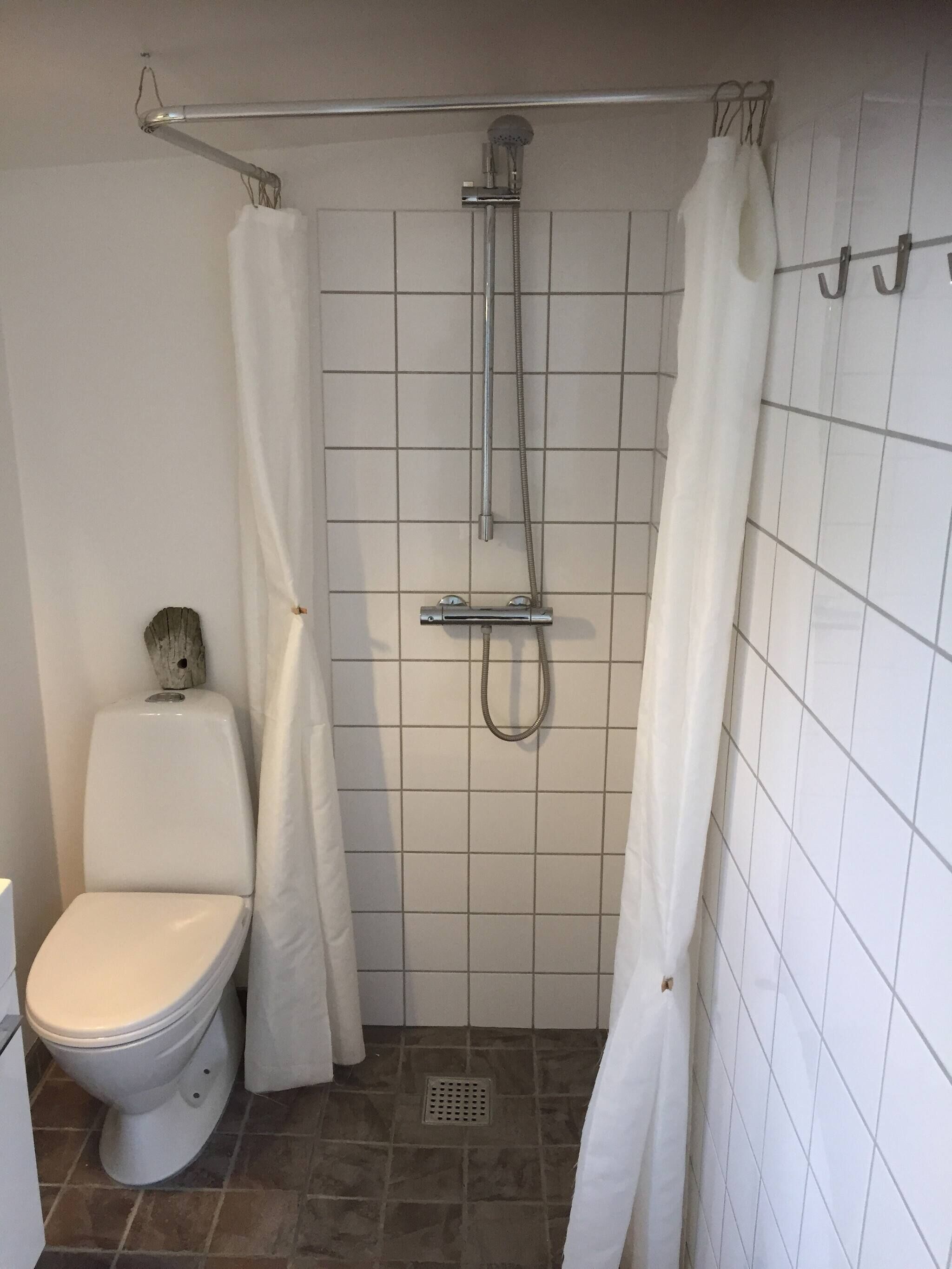 Ein Badezimmer mit Dusche, Toilette und gefliesten Wänden.