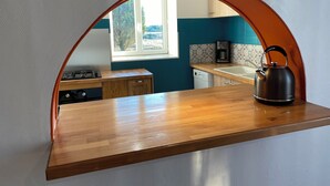 A kitchen with a wooden countertop, a kettle, and a window with a view of greenery. - Between land and sea (Marennes-Hiers-Brouage)