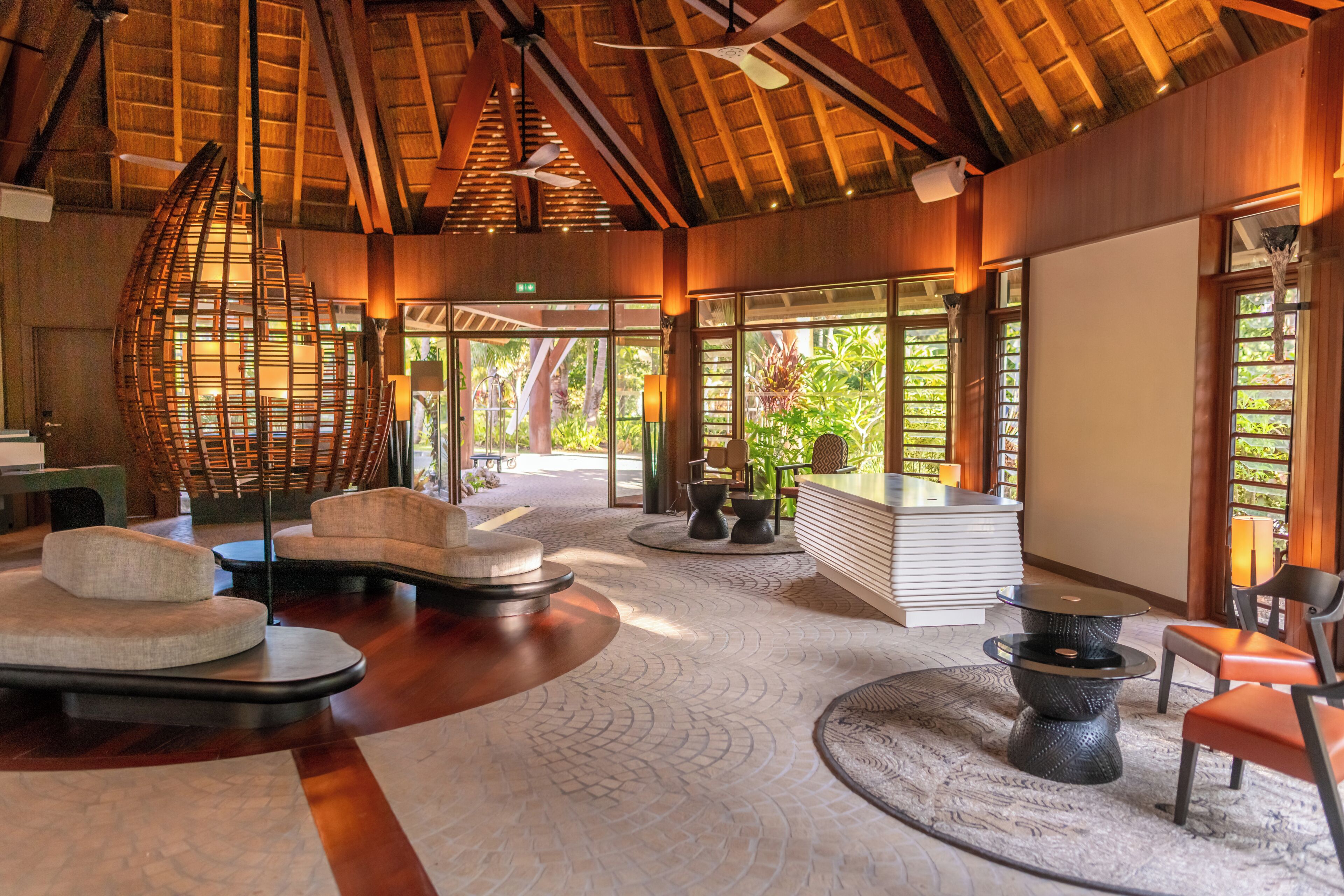 A spacious lobby with a high ceiling, a central seating area, and large windows offering views of the outdoors.