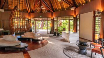 A spacious lobby with a high ceiling, a central seating area, and large windows offering views of the outdoors.