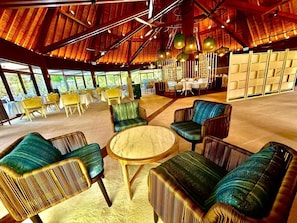 A spacious indoor area with high ceilings, round tables, and comfortable seating.