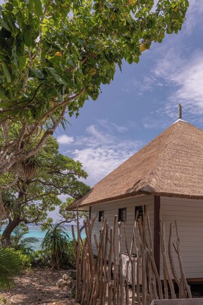 A thatched-roof building with a view of the ocean. - HOTEL WADRA BAY (Lifou)