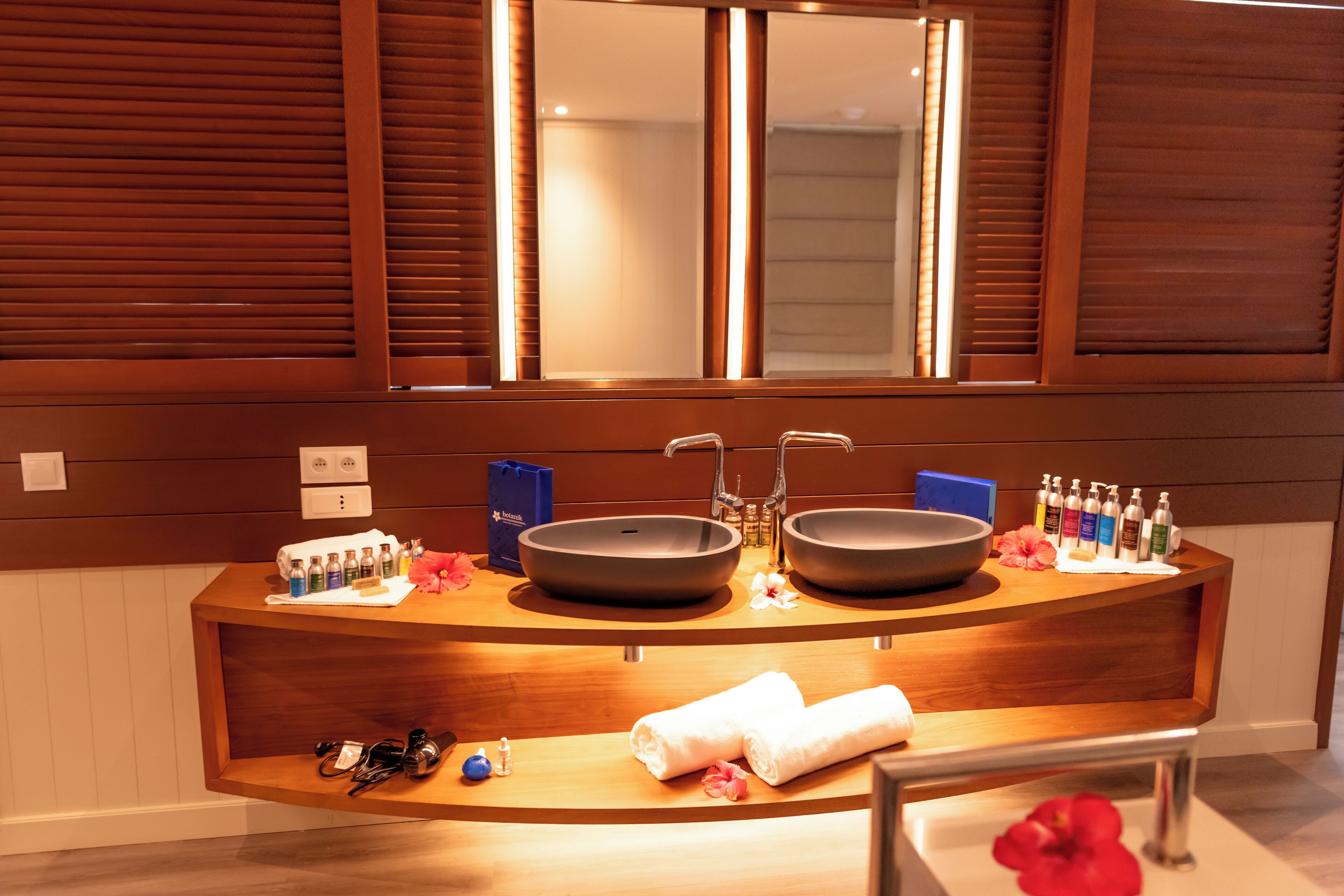 A bathroom with a wooden vanity, two sinks, and a mirror above.