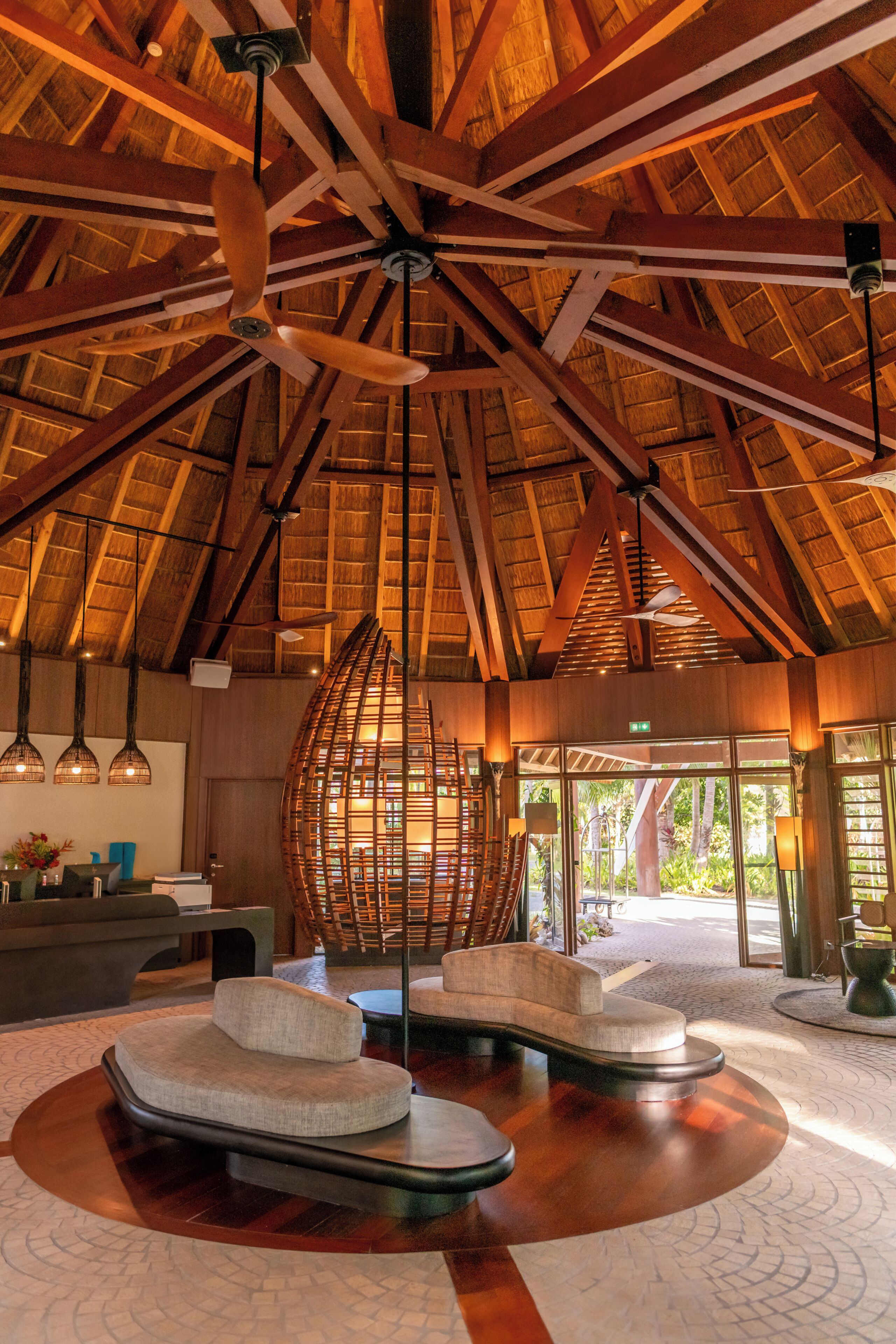 A spacious lobby with a high ceiling, wooden beams, and a large woven light fixture.