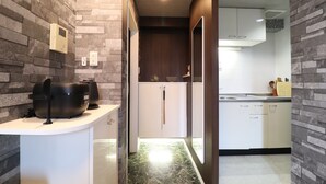 A modern kitchen with a stone wall backsplash, a built-in oven, and white cabinetry. - One Stay Shinsaibashi (Osaka)