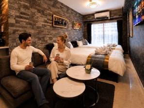 A modern hotel room with a brick wall, a large bed, a sofa, and a small round table. - One Stay Shinsaibashi (Osaka)