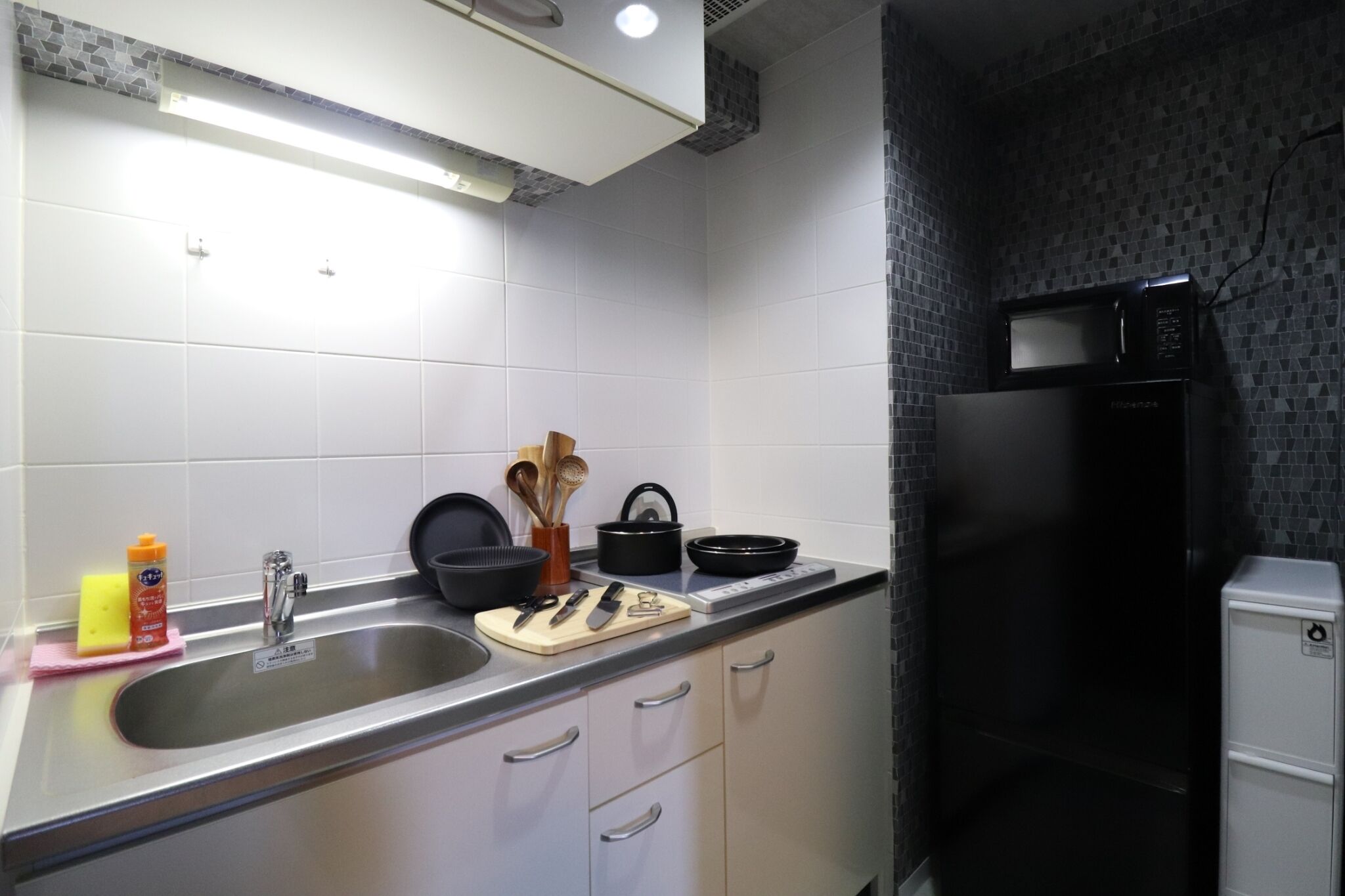 Een keuken met een roestvrijstalen spoelbak, een magnetron en een koelkast.