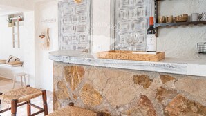 A rustic kitchen with a stone countertop, wooden chairs, and a wine bottle. - CostaBlancaDreams - Casa Hella in Calpe (Calpe)