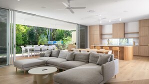 A modern living room with a sectional sofa, a round coffee table, and a dining area with a wooden table and chairs. - Navy'S By The Beach - Rainbow Shores (Rainbow Beach)