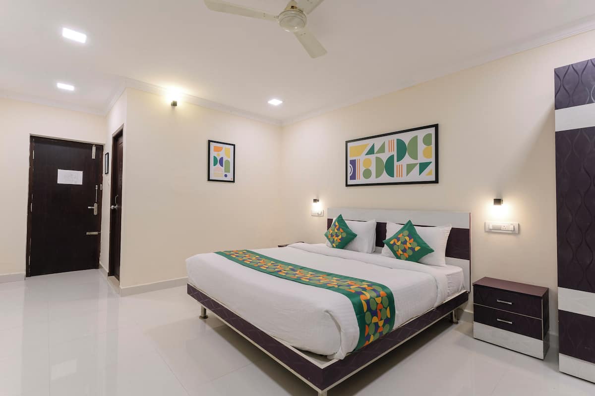 A modern hotel room with a large bed, bedside tables, and artwork on the walls.