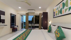 Habitación de hotel con cama, escritorio, silla, ventana y aire acondicionado.
