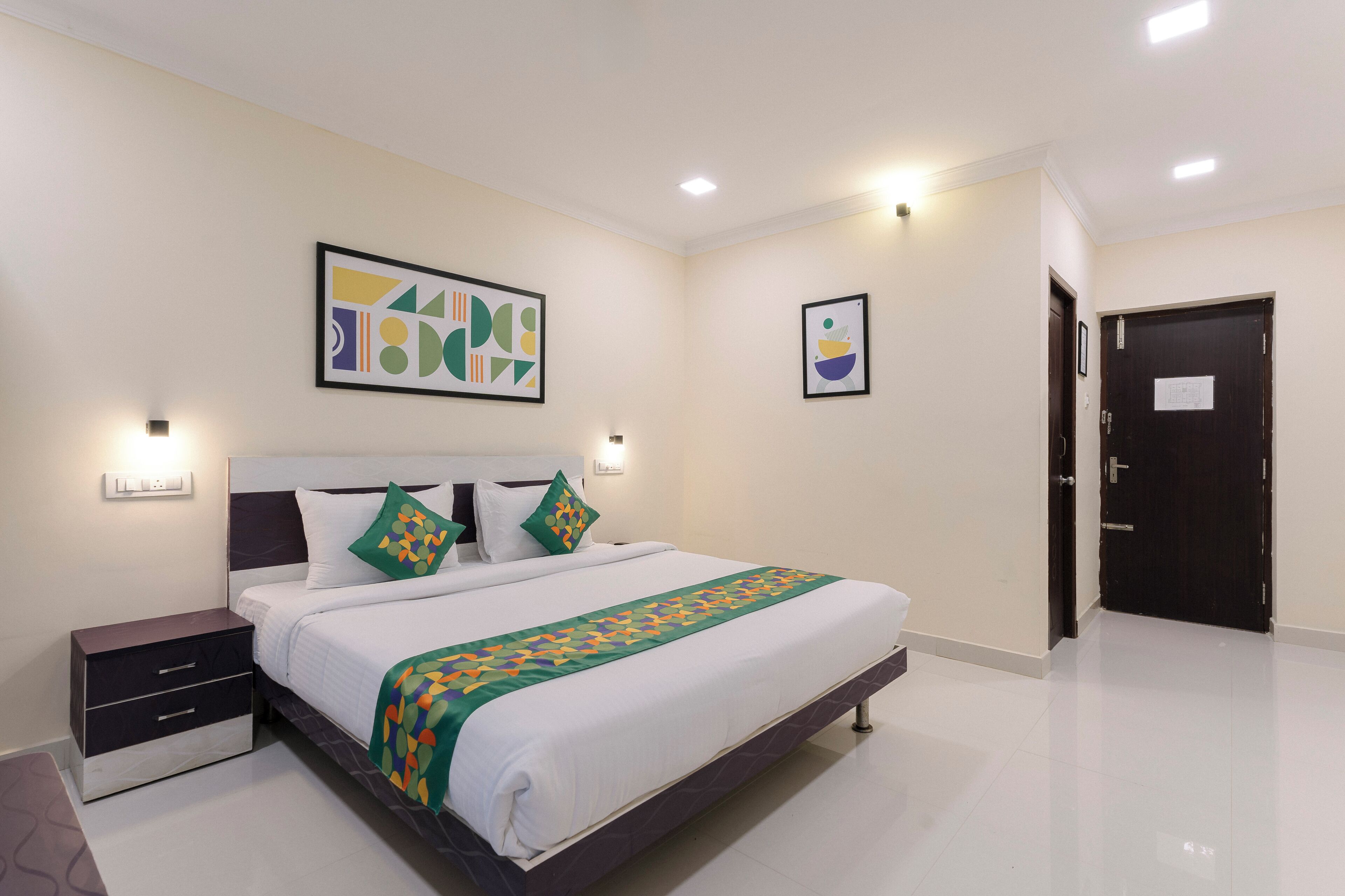 A modern bedroom with a large bed, bedside tables, and artwork on the walls.