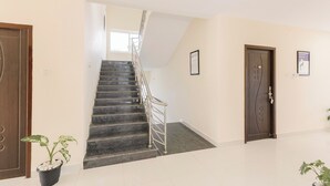 Un moderno vestíbulo de hotel con una escalera de mármol, un mostrador de recepción y una planta en maceta.