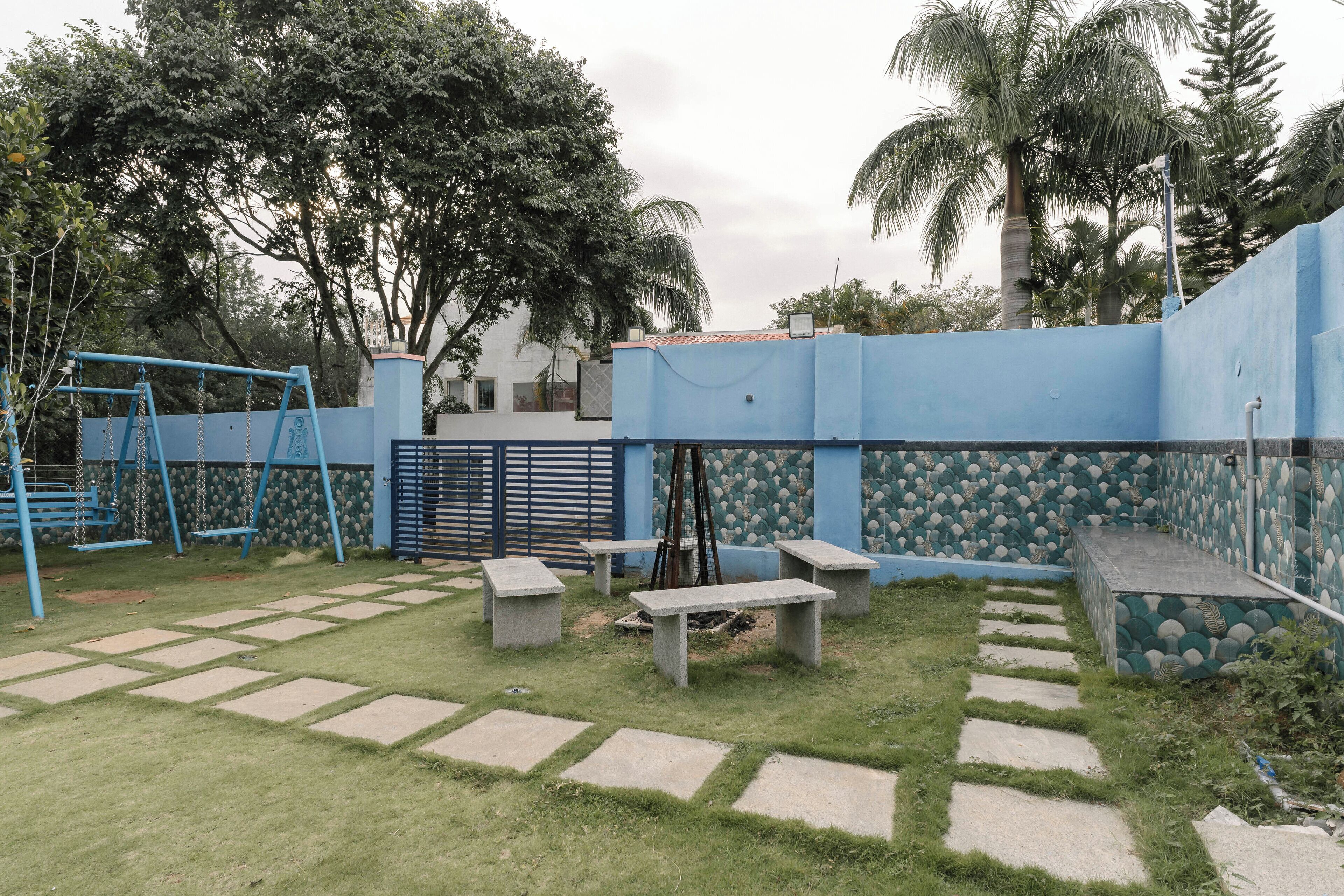 Un patio con un columpio, bancos y un muro decorado.