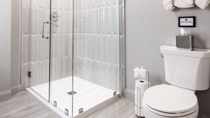 A modern bathroom with a glass-enclosed shower, a toilet, and a towel rack. - Hollyhock Suite 503: 2 bed/1 bath (Louisville)
