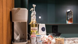 A coffee maker, a bottle of Monin French Vanilla syrup, and various condiments on a marble countertop. - Hollyhock Suite 504: 1 bed/1 bath (Louisville)