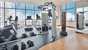 Ein modernes Fitnessstudio mit Laufbändern, Hanteln und einem Boxsack, ausgestattet mit großen Fenstern und Blick auf die Stadt.