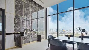 Ein moderner Büroraum mit großem Fenster und Blick auf die Stadt, einer Marmorwand und einem schlichten Tisch mit Stühlen.
