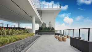 Eine Dachterrasse mit modernem Design, mit Betonboden, Geländer und einer Sitzgruppe mit Stühlen und Tischen.