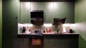 Una cocina moderna con horno empotrado, cafetera y diversos electrodomésticos.